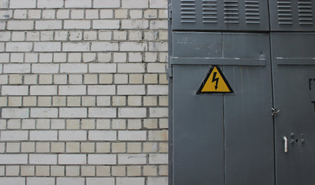 Steel Door Of Electric Booth With Triangular High Power Sign In Brick Wall