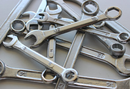 Laid out in disarray on top of each other chrome plated wrenches of different sizes