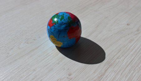 Sunlit model of the Earth with shadow on a wooden board detailed stock photo. A stock photo depicting time zones and time differences between continentsの写真素材