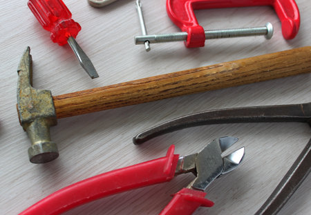 Carpentry tools and clamps are laid out on the surface of a wooden workbenchの写真素材