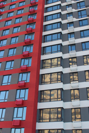 Painted Gray and Red Facade Of Modern Apartment House. Residential House Wall With Narrow Windows