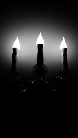 Vintage Style Wall Lamp in Three Candles Form Illuminate a Wall Black and White Vertical Imageの写真素材
