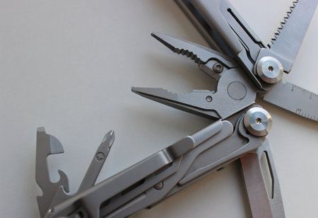Pliers And Blades Of Folded Pocket Multi Tool on White Surface Closeup View. Compact Tool for Multi...