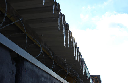 Metal canopy with hanging melting icicles. Cold drops falling from icicles detailed stock image