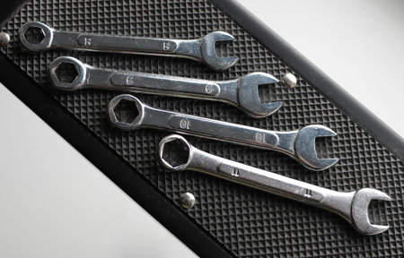 Black rubberized mat to prevent slipping with set of combination spanners on it over white background