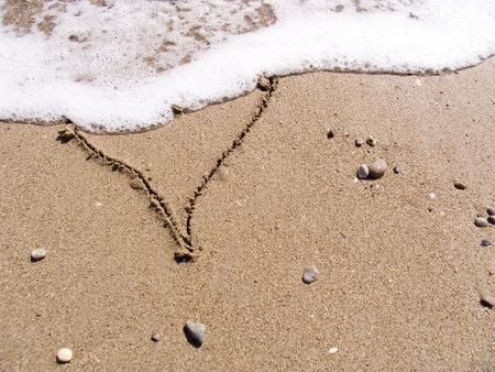 The inscription on sea sand as heart washes off a waveの写真素材