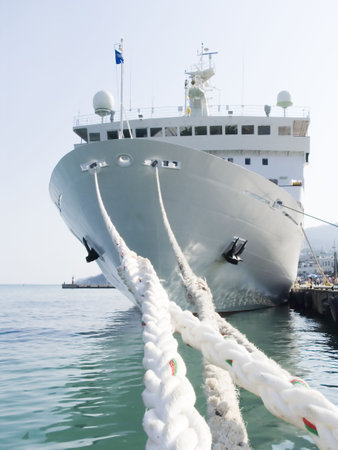 Berthing ropes on a pier with the big shipの写真素材
