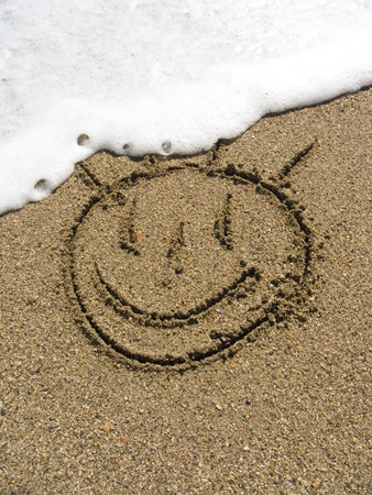 The smile is drawn on wet sea sandの写真素材