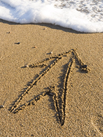 The arrow is drawn on wet sea sand