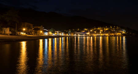 Sea town at night with lights reflecting in the sea, Moscenicka Draga, Croatiaの写真素材