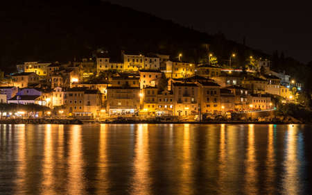 Sea town at night with lights reflecting in the sea, Moscenicka Draga, Croatiaの写真素材