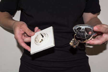 Person holding a damaged electric socket in her handsの写真素材