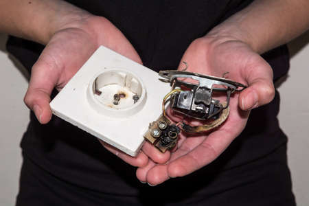 Person holding a damaged electric socket in her handsの写真素材