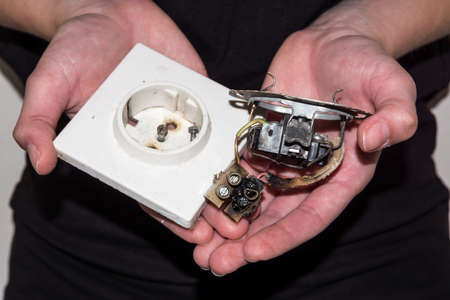 Person holding a damaged electric socket in her handsの写真素材