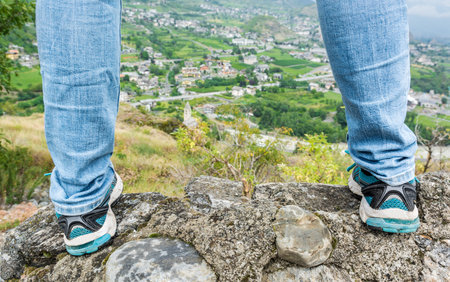 Rear view of a woman standing on a wall with a view of a town