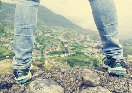 Rear view of a woman standing on a wall with a view of a townの写真素材