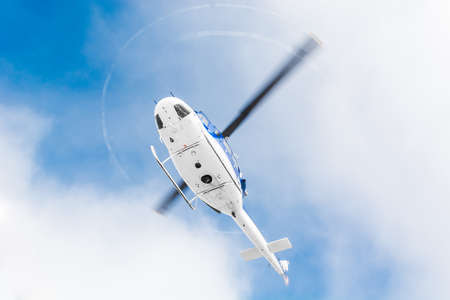 Helicopter flying under sky covered with cloudsの写真素材