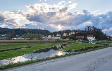 Flooded land in front of houses under setting sunの写真素材