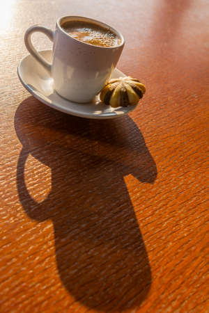 Cup of coffee with a biscuit on a wooden tableの写真素材