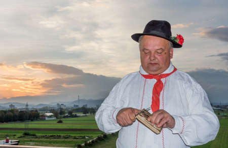 Man wearing traditional clothing cutting bacon at sunriseの写真素材