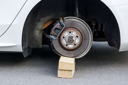 Car with stolen wheels. White vehicle left on wooden bricks.の写真素材