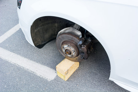 Car with stolen wheels. White vehicle left on wooden bricks.