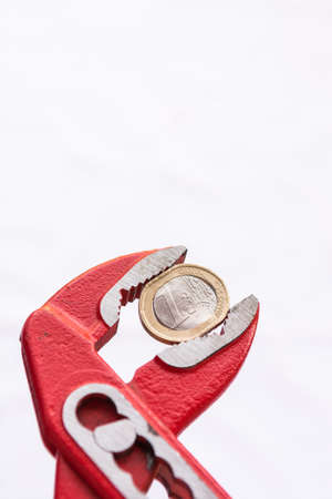 Euro coin squezzed with pliers. Euro zone crisis.の写真素材