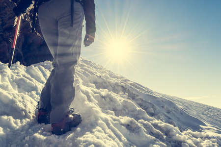 Close up of hiking shoes with crampons. Alpinist ascending a snowy mountain.の写真素材