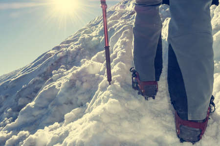 Close up of hiking shoes with crampons. Alpinist ascending a snowy mountain.の写真素材