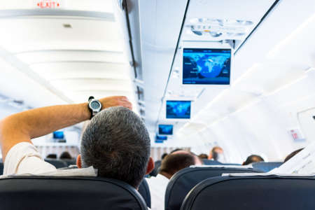 Airplane interior. Passanger looking at wrist watch.の写真素材