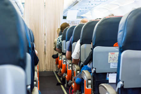 Airplane interior. Cabin aisle with close up of people sitting.の写真素材