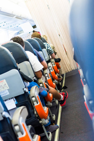 Airplane interior. Cabin aisle with close up of people sitting.の写真素材