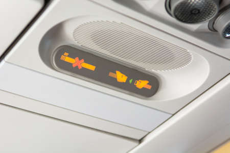 Airplane interior. Close up of no smoking and seat belt safety sign.の写真素材