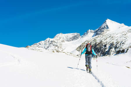 Ski touring in sunny weather. Female skier ascending a trail.の写真素材