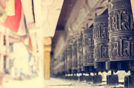 Closeup of Tibetan praying wheels. Traditional vilage entrance.