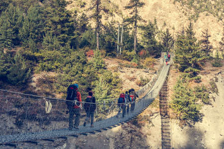 Trekkers crossing a suspension bridge. Group of people on their way through Annapurna region in Nepal.の写真素材