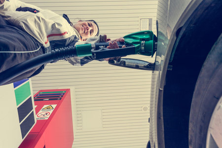 Attractive woman pumping gas at gas station. View from under the nozzle.