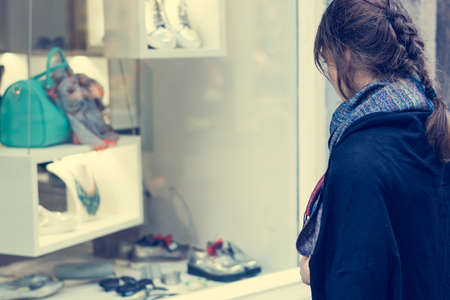 Young and attractive lady window shopping. Deciding what to buy. Customer in shopping street.の写真素材
