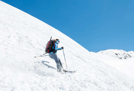 Female skier tackling a steep slope. Ski touring in the mountains.の写真素材