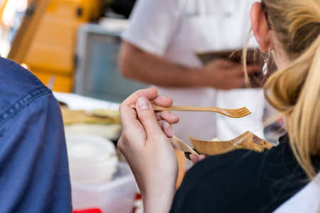 Attractive young blonde woman enjoying street food. View from the back.の写真素材