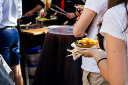 Woman holding a tasty potatoe dish. Outdoor food event.の写真素材