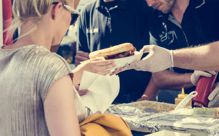 Attractive woman ordering a plate of delicious food. Street cousine event.の写真素材