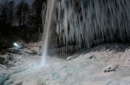 Person illuminating frozen waterfall.の写真素材