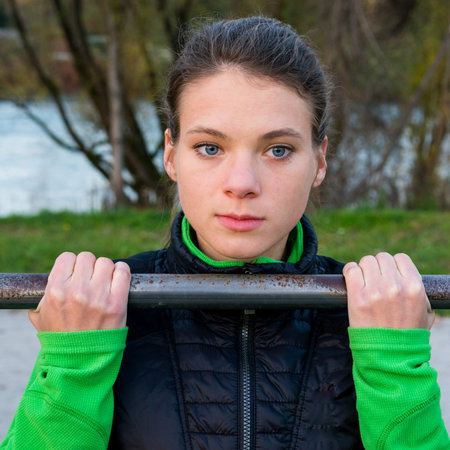 Attractive brunette doing pullups in park.