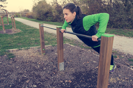 Attractive brunette doing pushups in park.