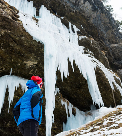 Active young woman looking at frozen icicles.