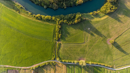 River bend surrounded by fields from birds eye view.