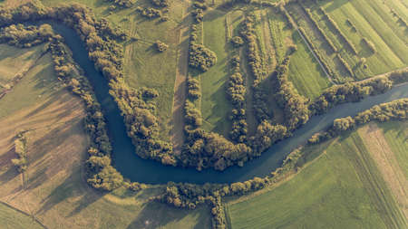 River bend surrounded by fields from birds eye view.の写真素材