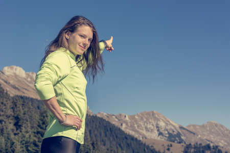 Female hiker pointing at mountain peak.の写真素材