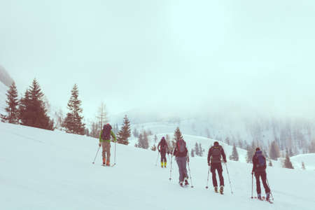 Group of back country skiers walking through a misty valley.の写真素材